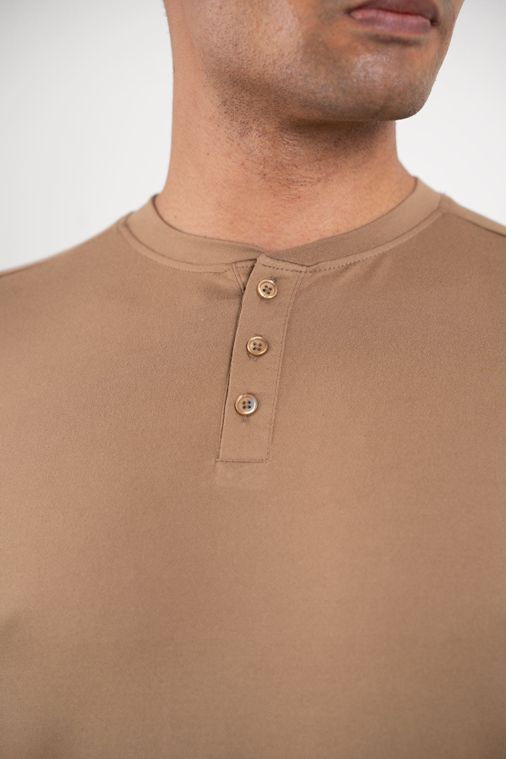 Close-up shot of the fabric of the beige Henley t-shirt, revealing its soft and smooth texture