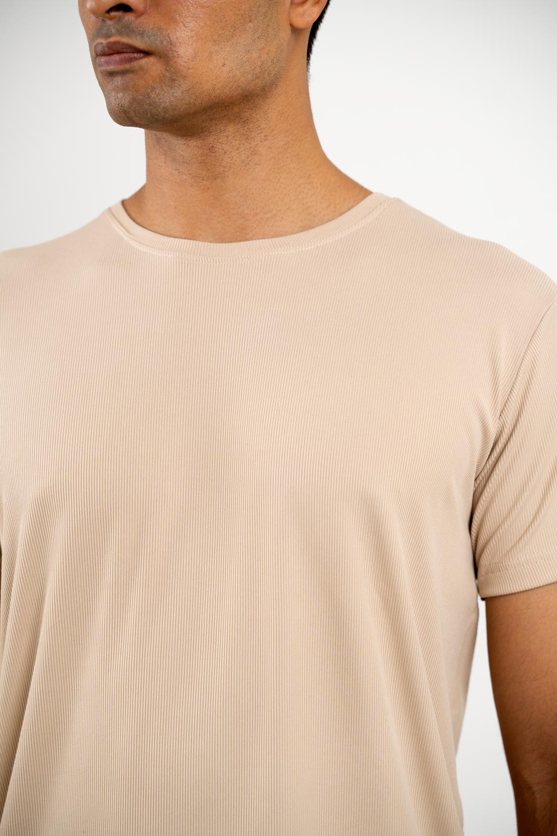 Detailed close-up of the stitching and neckline of the beige crewneck tee, showcasing its quality construction